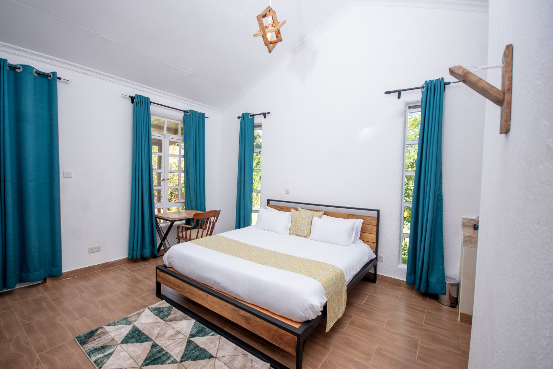Contemporary guest bedroom with teal curtains, reclaimed timber and steel bed frame and vaulted white ceiling